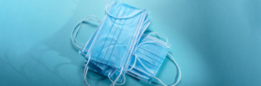 Disposable face masks stacked together on blue background