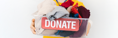 Person holding clear donation bin with old assorted clothes