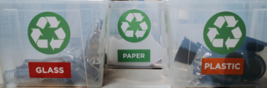 People sitting on chairs near plastic recycling containers for glass, plastic, and paper