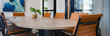 photo of meeting room. There is a large table surrounded by leather office chairs.
